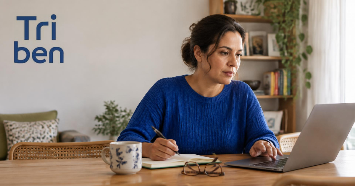 Mulher comparando opções de plano de saúde no notebook, na mesa de casa, com uma xícara de café ao lado